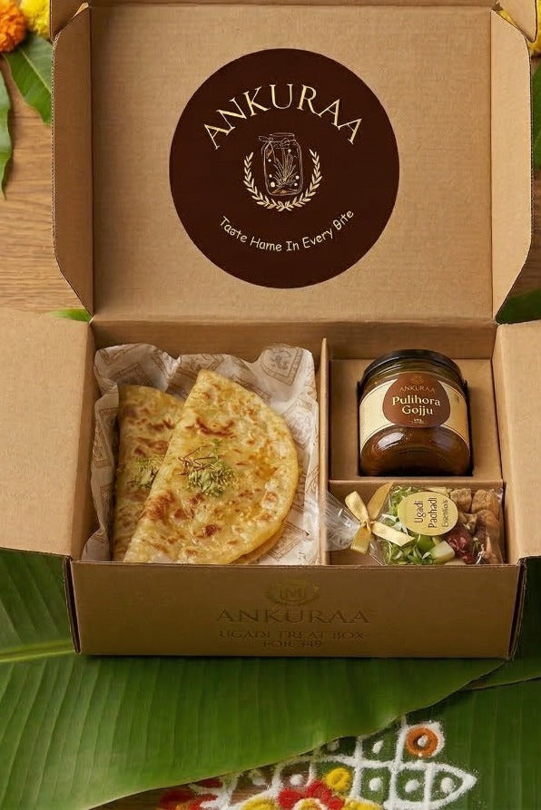 Open cardboard box containing food items on a decorative table with flowers and leaves.
